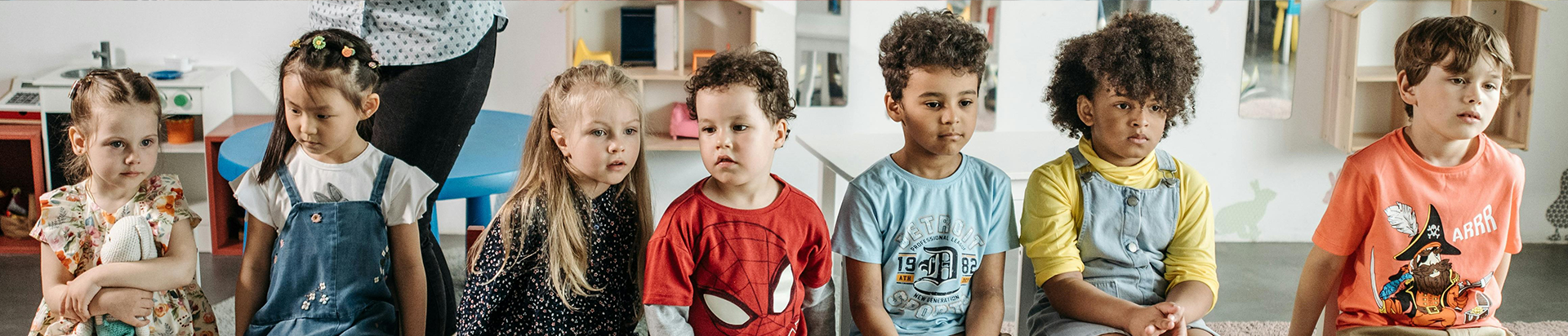 Young group of diverse children sit in a row on chairs